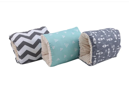 Three rolled fabric baby blankets with different patterns are displayed side-by-side on a plain white background. The left blanket features a black and white chevron pattern, the middle blanket is light blue with small white triangle prints, and the right blanket is slate blue with white fish prints.